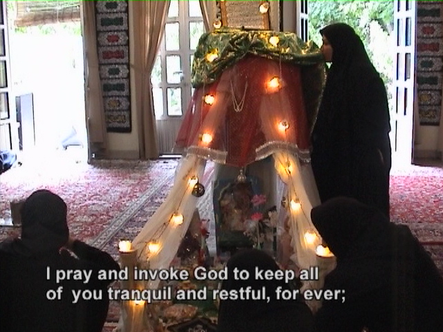 A woman kissing the votive fabrics on the proxy shrine of Ruqayyeh before the commemoration ceremony begins.