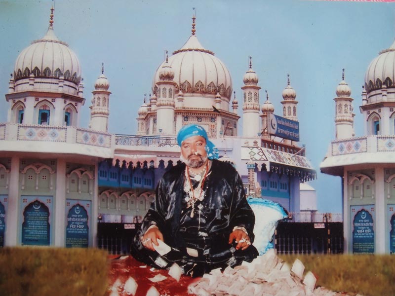 An image of fourth sajjada nishin Sai Gulam Baqi Bille Shah seated beside a hoard of currency notes and Mandhali Sharif in the backdrop 2011 -- Yogesh Snehi