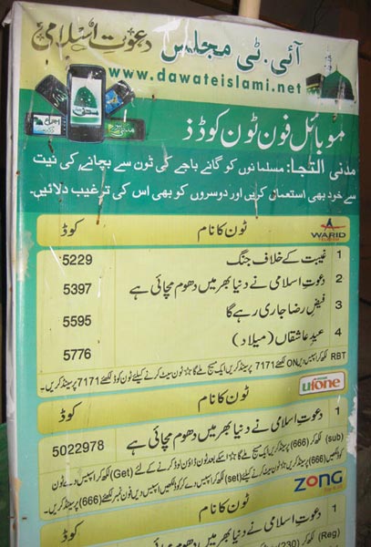 A huge panaflex banner listing codes for downloading religious caller tunes. This is pasted on the wall near the entrance of Faizan-e-Madina.